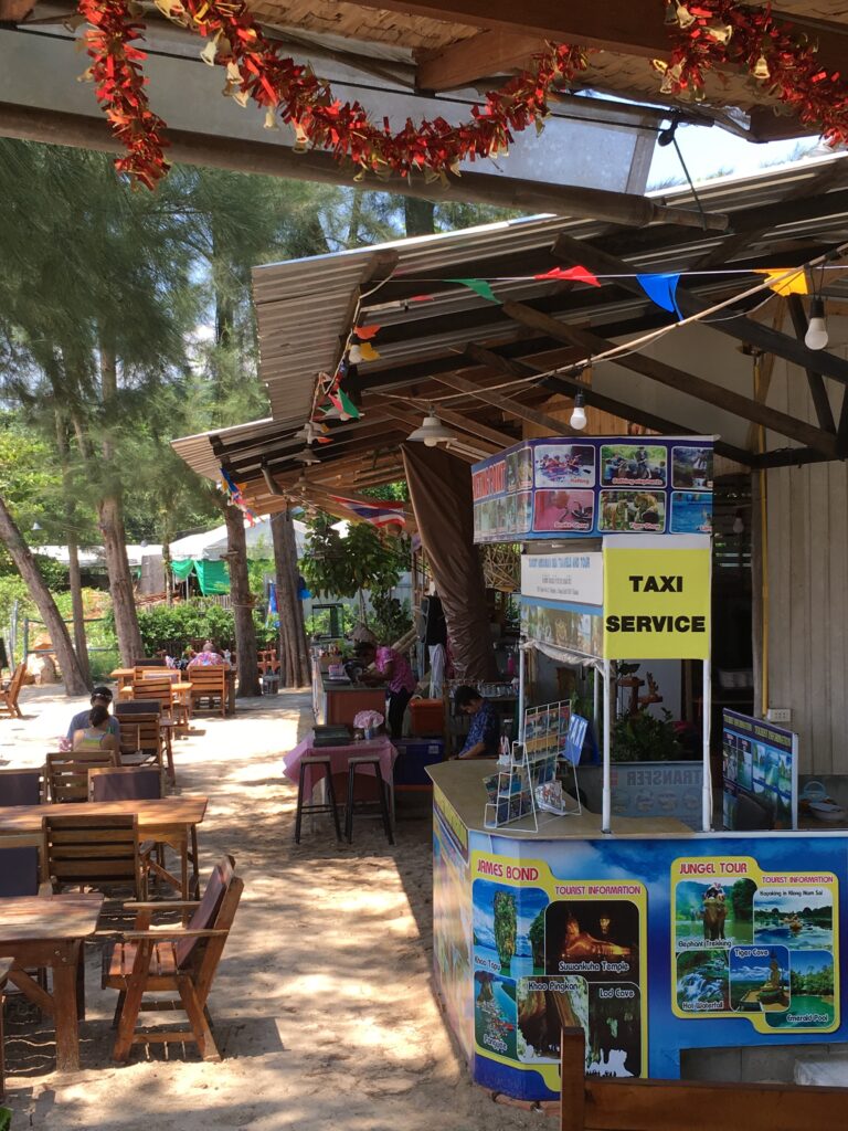 Beach front street with a local travel agent advertising trips from Krabi, Thailand.