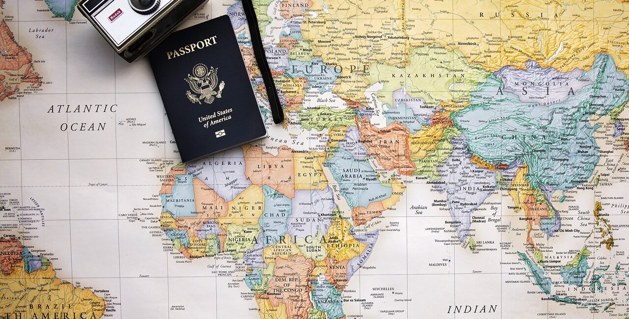 Map of the World with a passports and camera sitting on it.