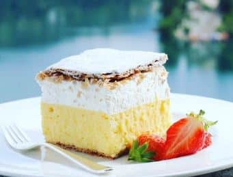 A layered yellow, white cake with a strawberry and crisp topping.