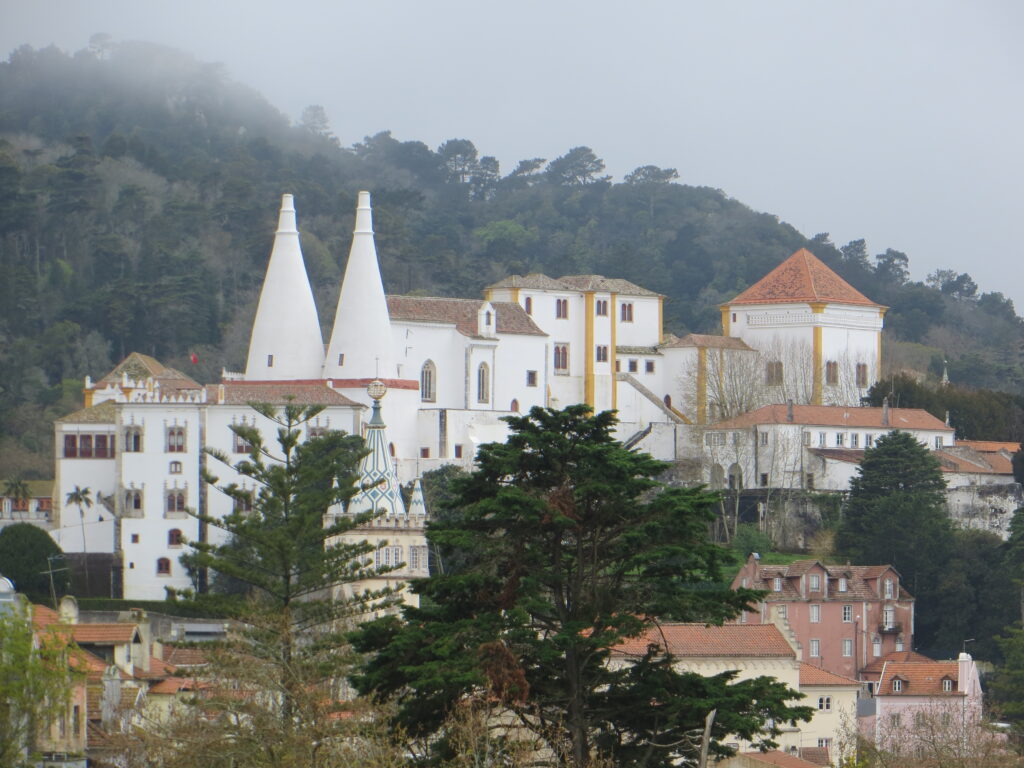 Pena Royal Palace near Lisbon, now a museum. It has 2 spires and and the main building is painted white and yellow.