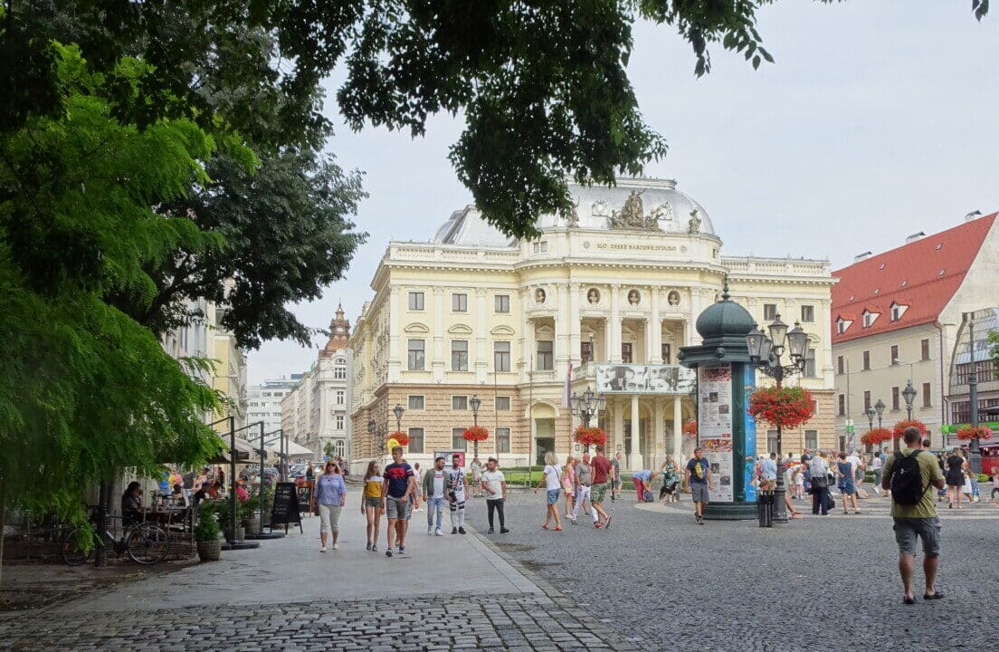 National Theatre Building with people walking on a wide avenue leading to the white building.