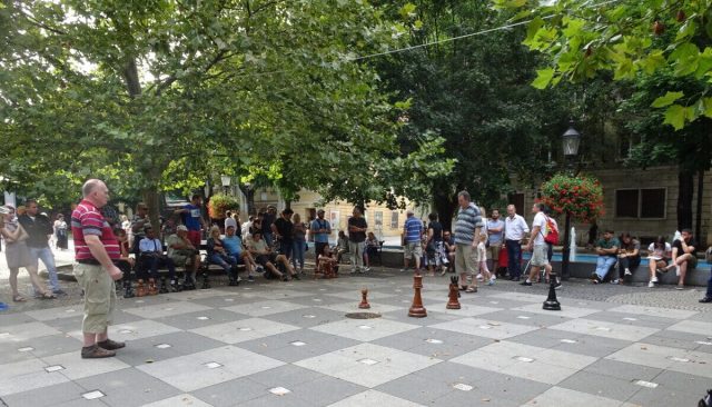 Men are playing chess on a large scale board within a park in Bratislava.