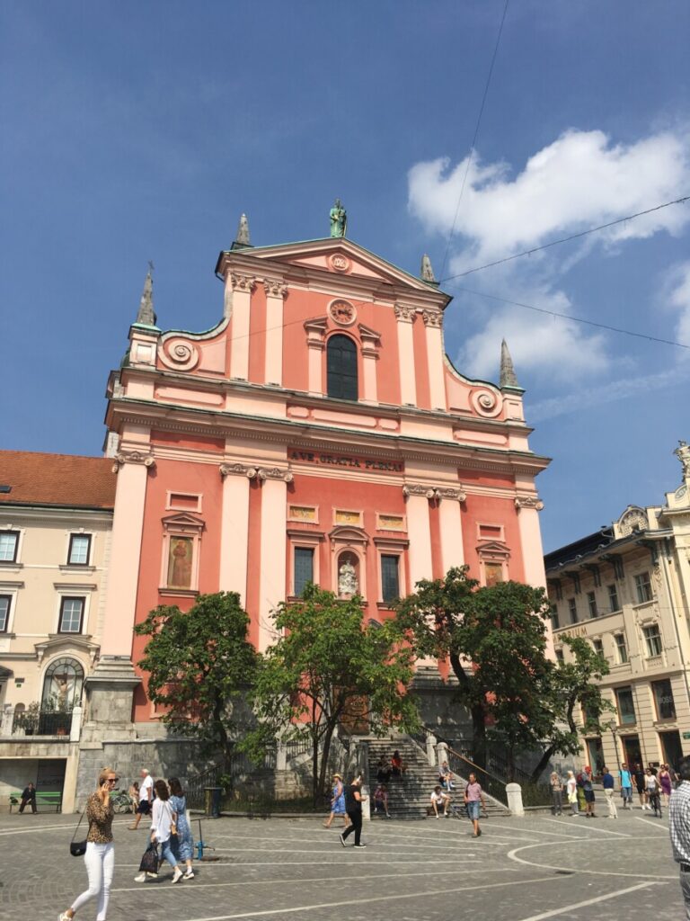 Preseren Square with churches and local government buildings in red and pink brick colors.