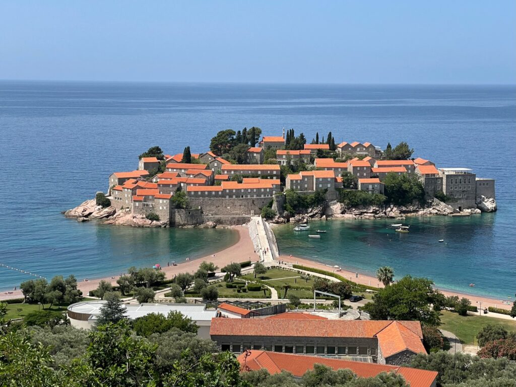A man made island off Montenegro which is a private resort. Red tiled roofs and a causeway can be seen from the mainland.