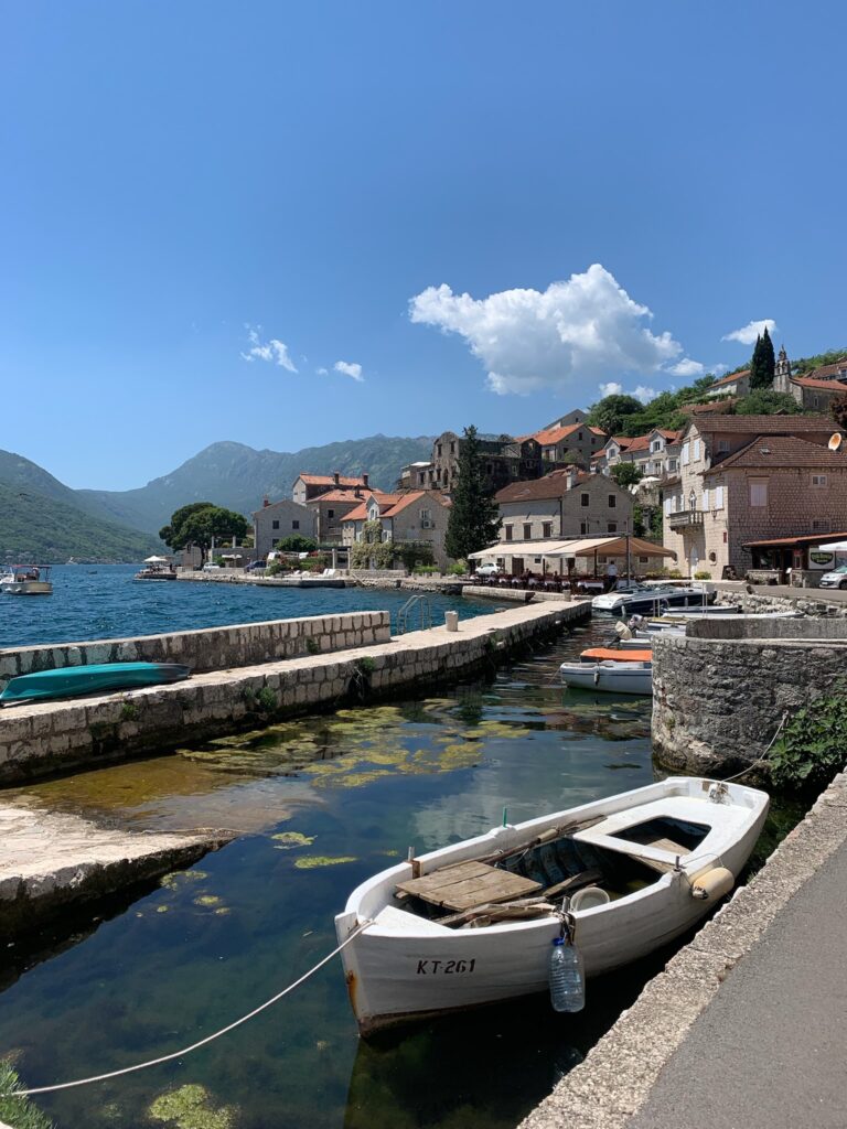 Boats moored at a harbour in Perast Montenegro against a stone harbour wall.