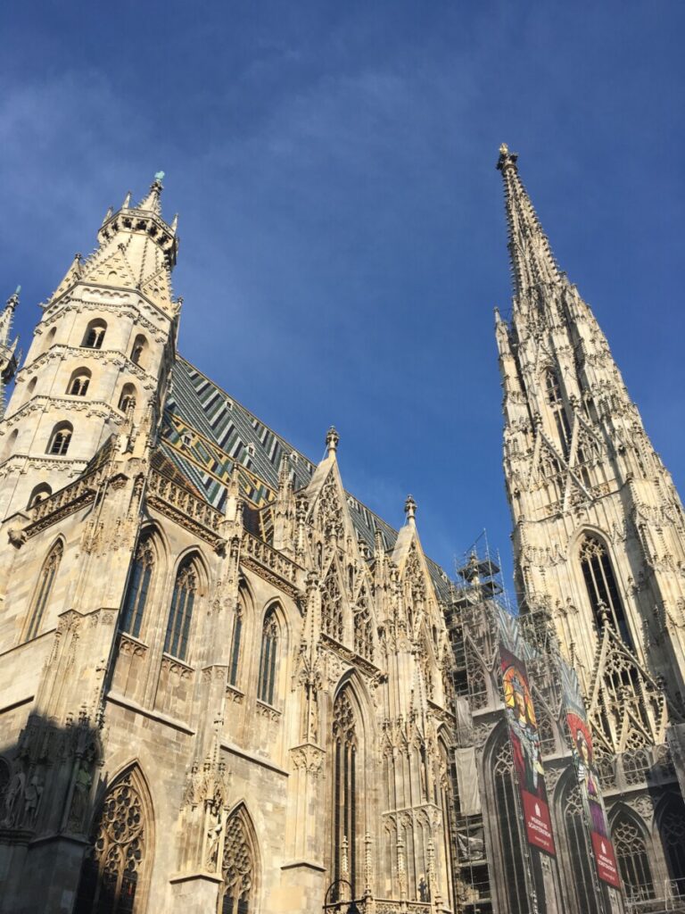 Towers and spires in light stone fill the sky in Vienna. This is St Stephen's Cathedral.