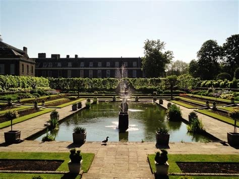 Kensington Gardens in central London with a large pool surrounded by shrubs.