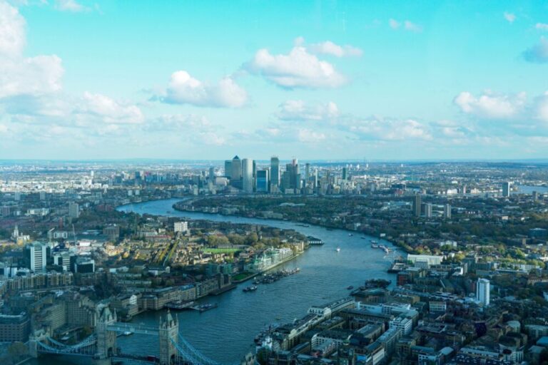 Skyline of Real London with River Thames flowing through both banks that are full of buildings and in the distance the central part of London.