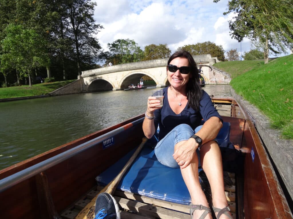 Woman sitting in a boat in Cambridge with a glass of wine in her hand.