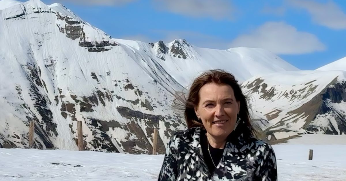 A woman standing in front of large snow covered mountains in Kazbegi Region of Georgia.