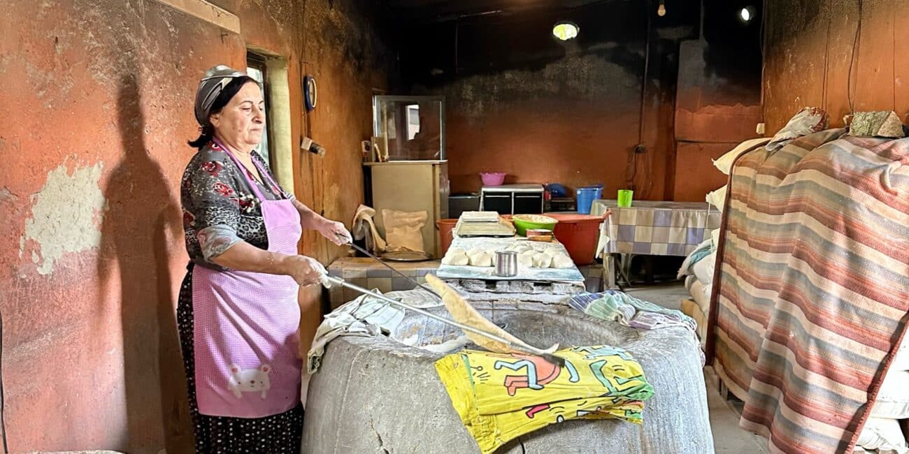 A woman in making fresh breads in a wood fired oven.