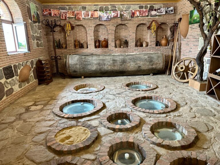 A photo of a wine cellar in the country of Georgia with glass round covers sunk into a stone floor.