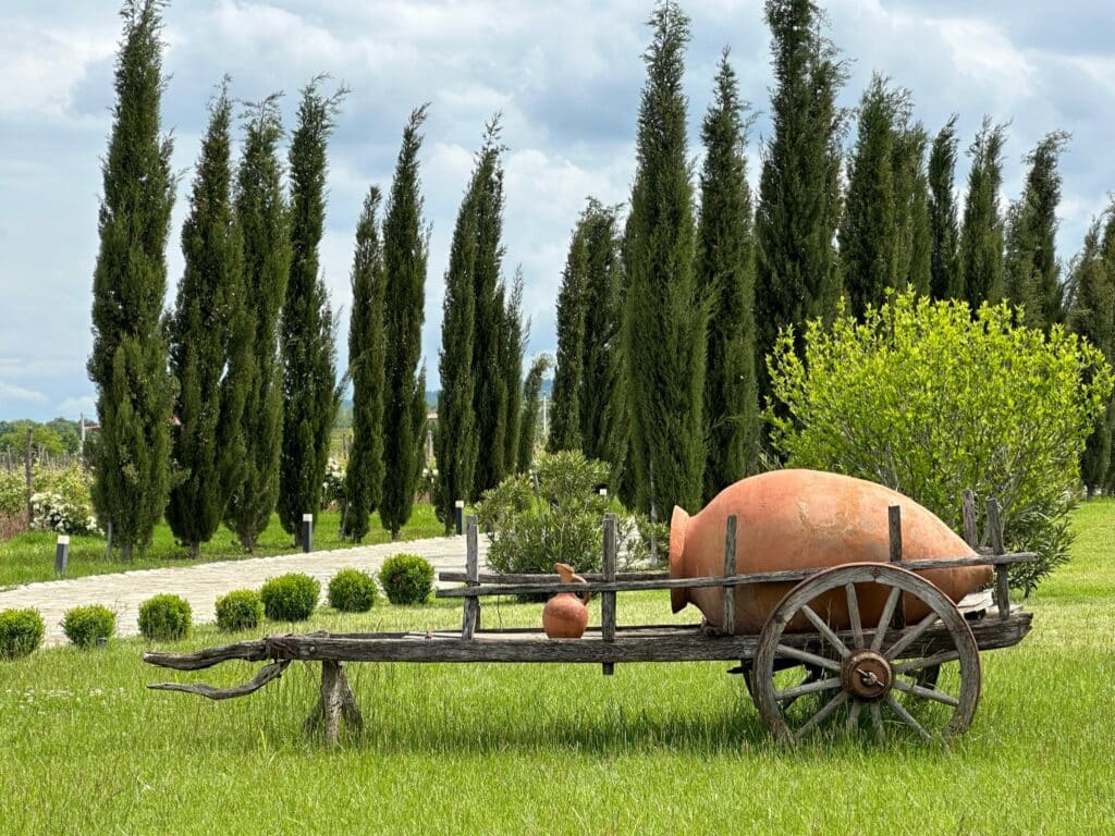 An ancient clay wine storage pot is displayed on a wooden cart for decor at the entrance of a Georgian winery.