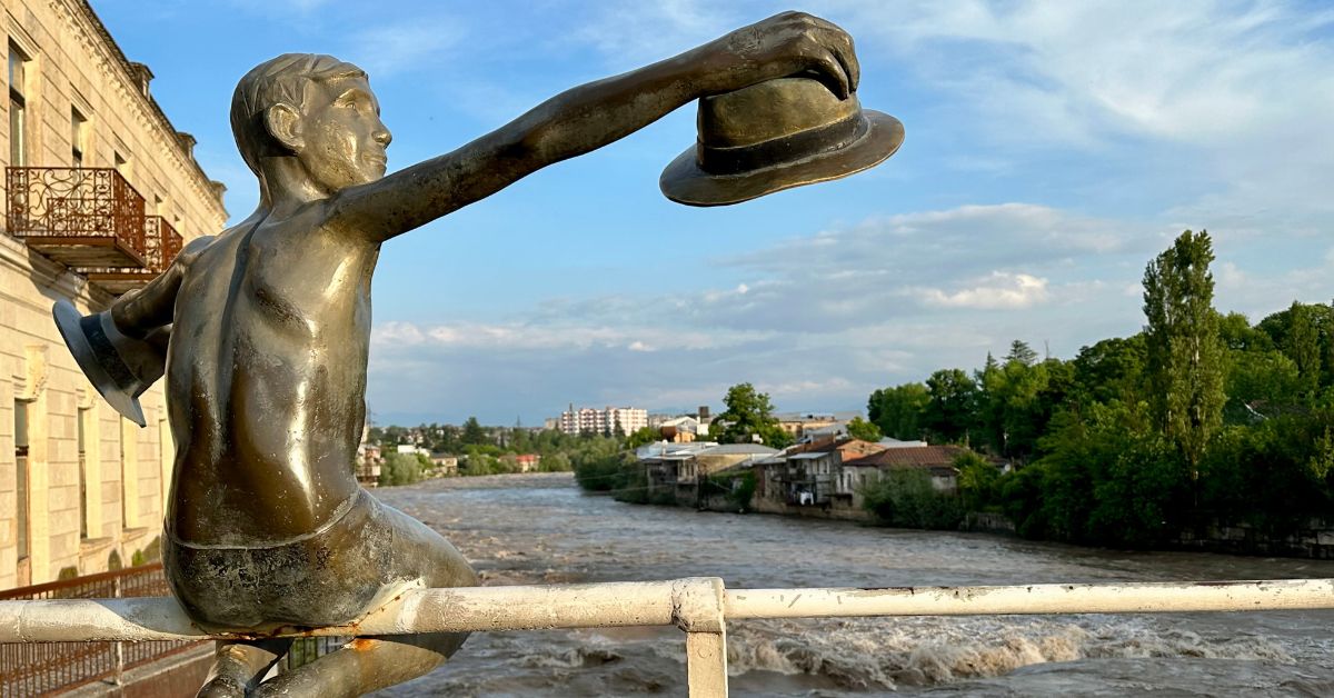 A bronze statue of a boy with a hat is on the handrails of the White Bridge, a popular tourist attraction in Kutaisi Georgia.