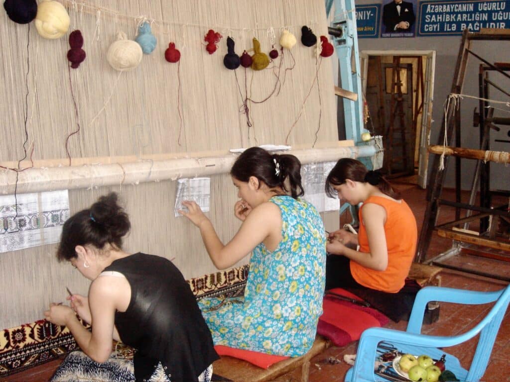 Three Carpet weavers working at a loom in Quba, north of Baku, Azerbaijan. They continue ancient weaving traditions.