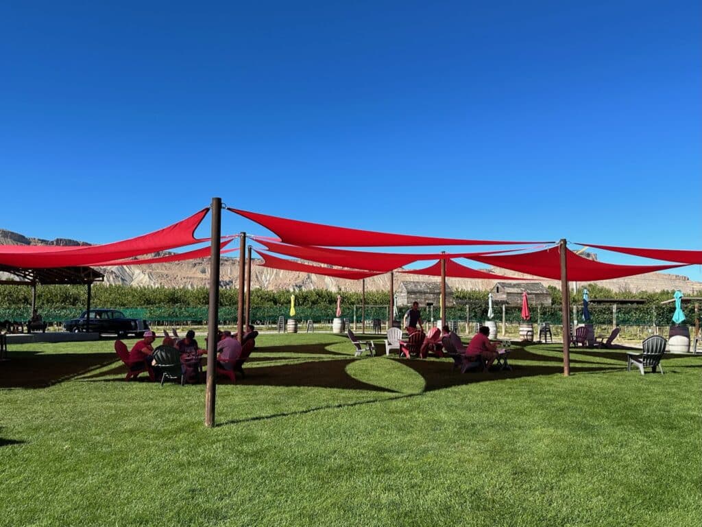 Winery in palisade Colorado with a red tent structure for guests to relax on a grass area next to vineyards