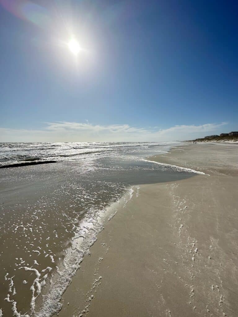 Sandy beach with sunshine radiating off the gentle waves on Amelia Island, Florida.