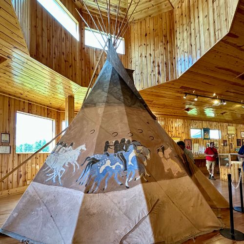 Traditional home exhibit within the Indian Museum of North America shows paintings of people on horseback.