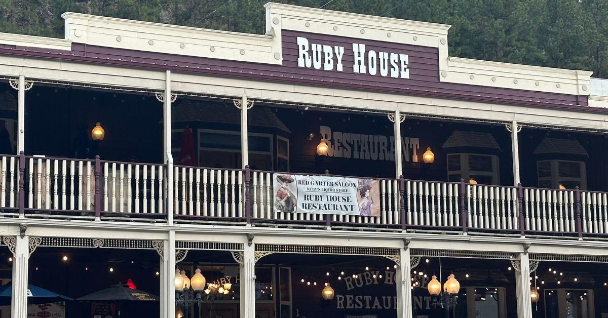 A western style wooden building with a wrap around balcony. The name Ruby House is displayed on top of the building.