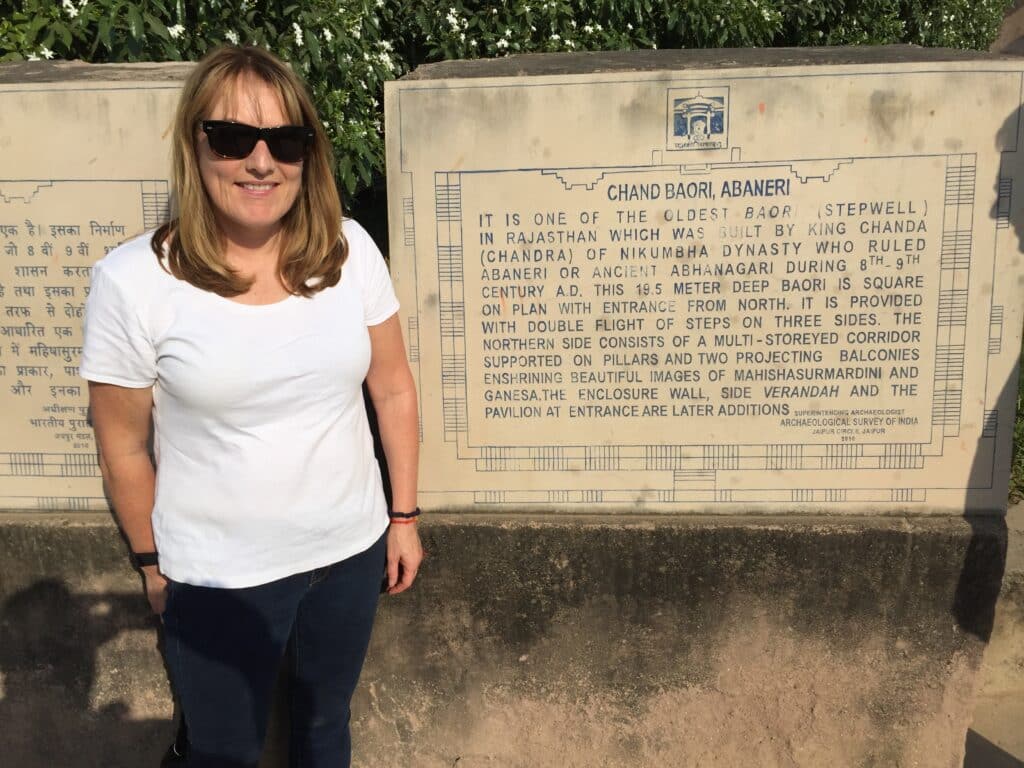 Woman standing next to an entrance map of an ancient Indian well system.