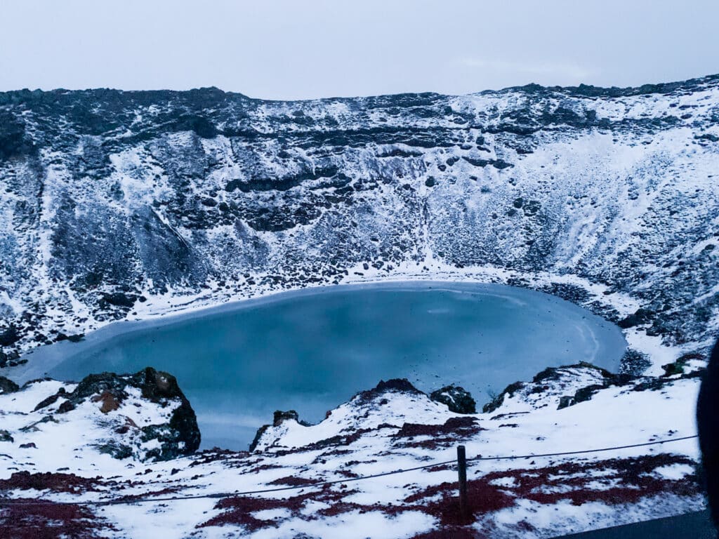 Iceland Golden Circle's Kerid Lake Crater in winter with azure blue frozen water.