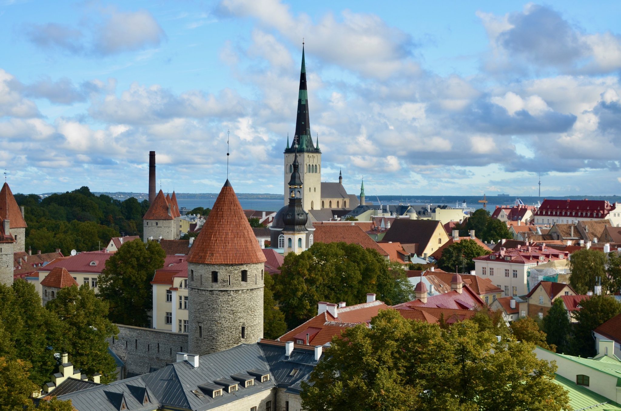 View over the city of Tallinn, Estonia in the Baltics with church spires , red tiled rooftops and beyond them coastal waters.