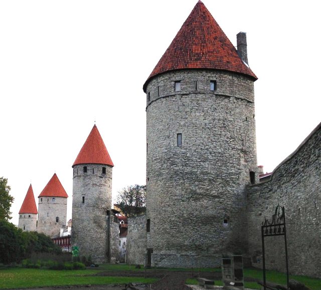 Old City Wall Tallinn with remaining towers which have red tiled roofs.