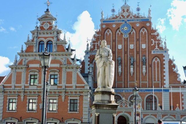 House of the Brotherhood of Blackheads with red brick and gothic design. In front is a statue.