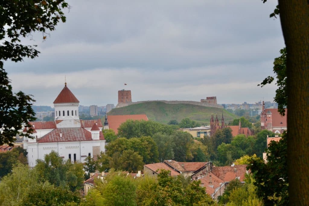 Scene of the city of Vilnius Poland in fall colors with trees turning colour and medieval spires ion the distance.