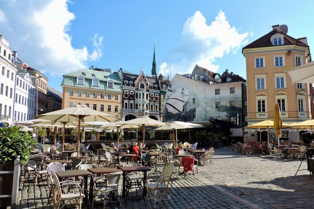 Central Square in Riga with cafe tables and umbrellas facing multi-coloured buildings.