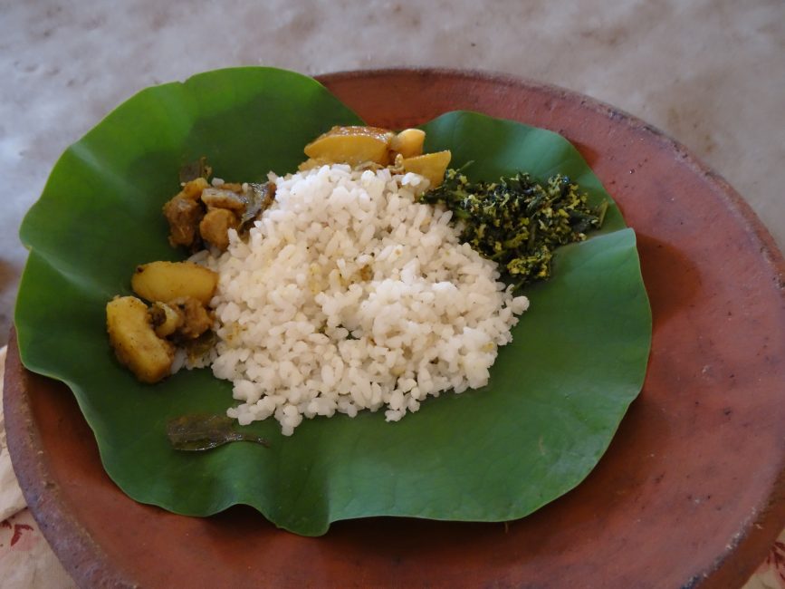 Rice and vegetables are served on a green lotus leaf which is a tradition in Sri Lanka