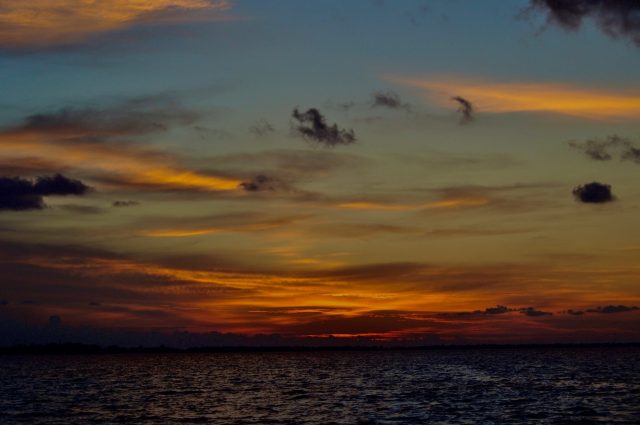Sunset in the India Ocean with bright red, orange, blue and greens mixed in with clouds over the water.