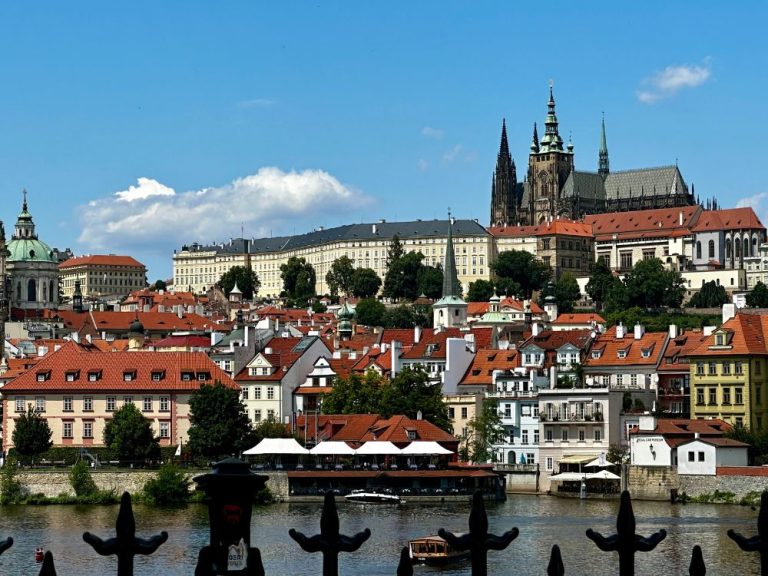 View of Prague city from river shows why Prague is worth visiting. Castle towers, medieval buildings flow down from the hillside to the river.