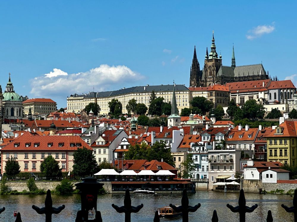 View of Prague city from river shows why Prague is worth visiting. Castle towers, medieval buildings flow down from the hillside to the river.