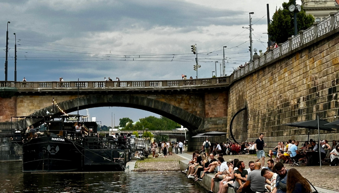 People sitting on the edge of the river in Prague. This is a perfect way to spend an evening when visiting the city.
