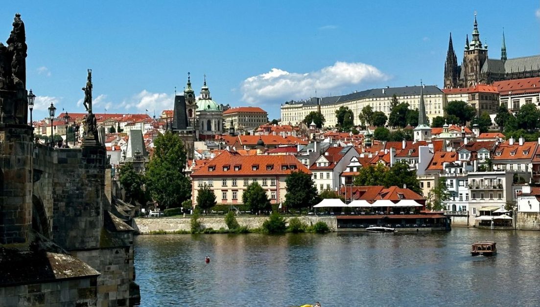 View of Old Town Prague and its river. Red roof buildings fill the town.