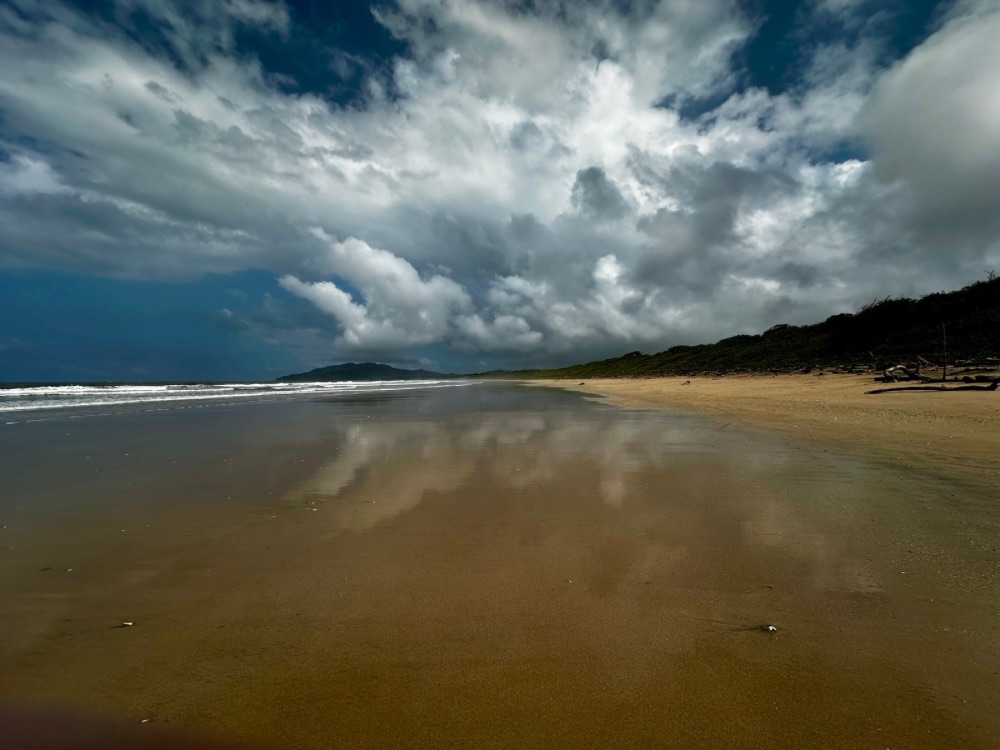Beach at Playa Grande with clouds reflected in the shallow waters and sandy beach.