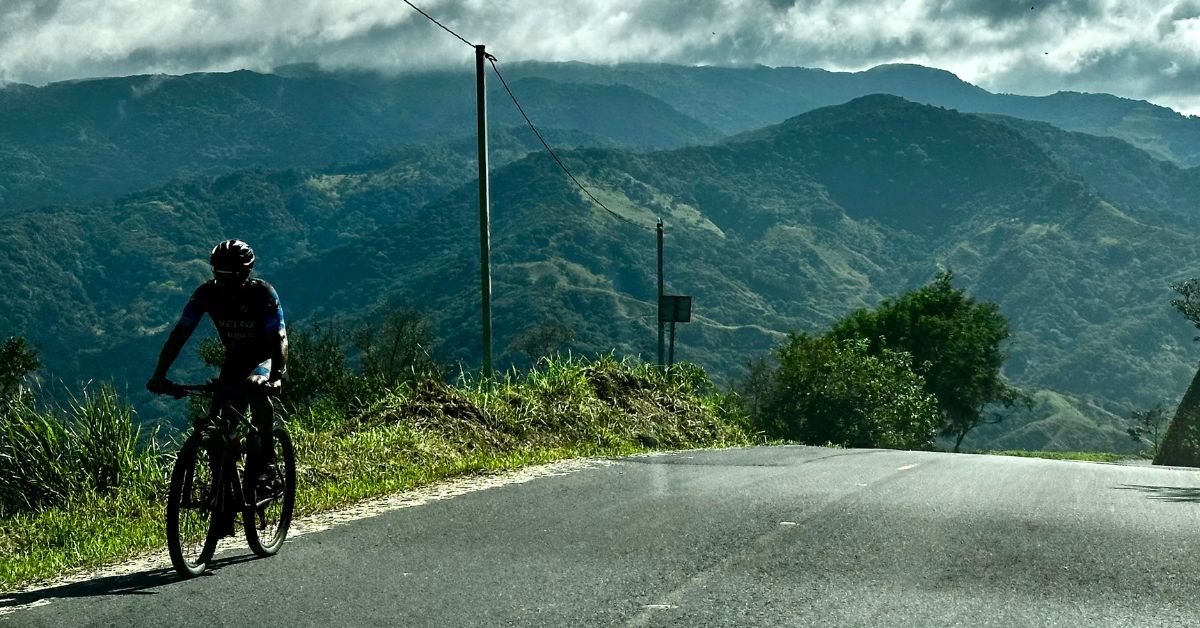 Steep mountain roads in Monteverde with a cyclist nearing the summit.