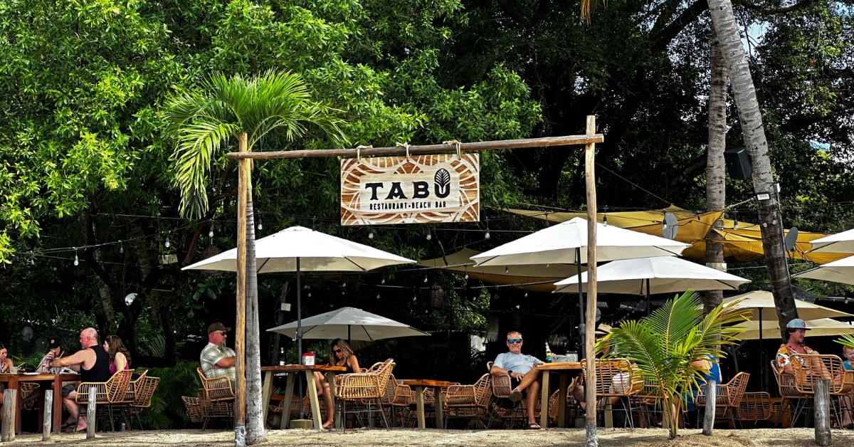 People sitting at restaurant tables on the beach.