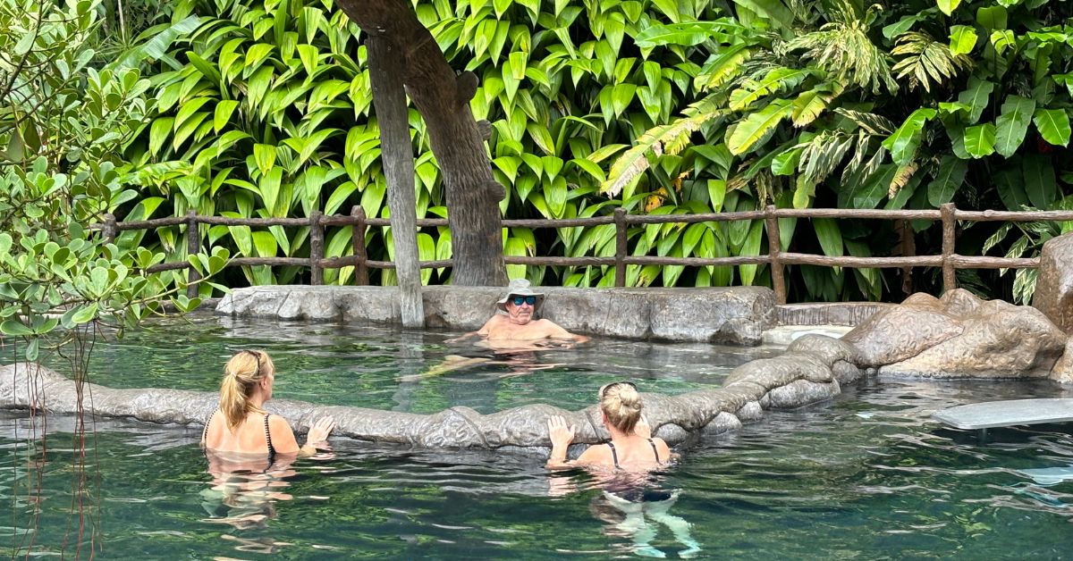 Three people bathe in hot water springs