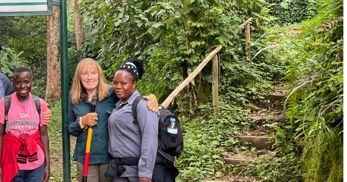 2 Porters with a trekker stand at the start of the forest area in bwindi Uganda.