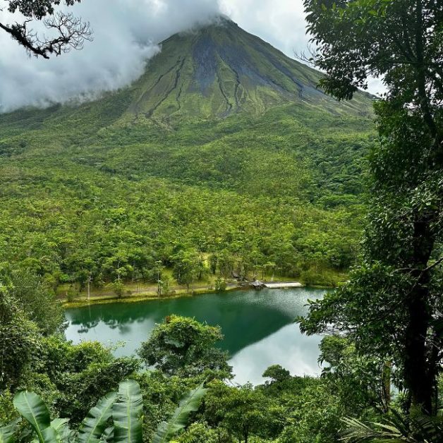 Lookout point to view Arenal Volcano which is puffing smoke. At base of the volcano there is a lake.