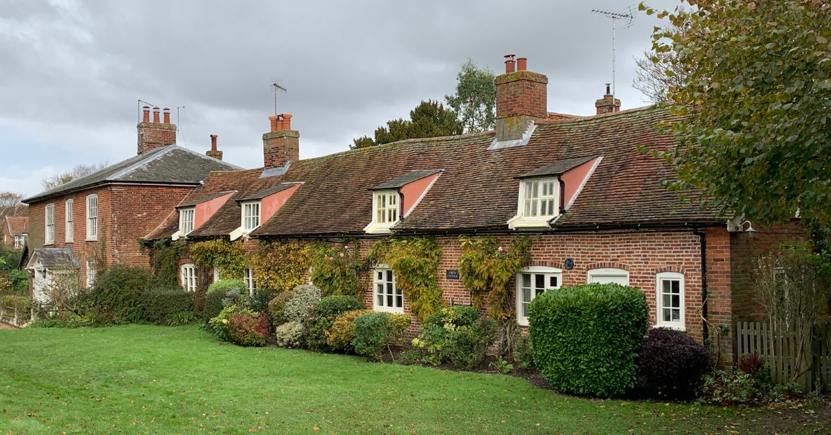 Row of country cottages with red brick and shrubs around them