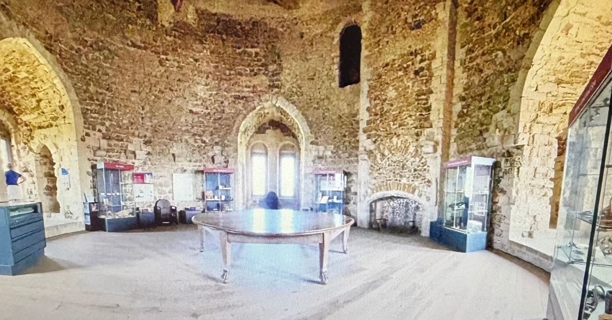 Inside Orford Castle with a large ornate table in the middle and exhibit cabinets around the stone walls