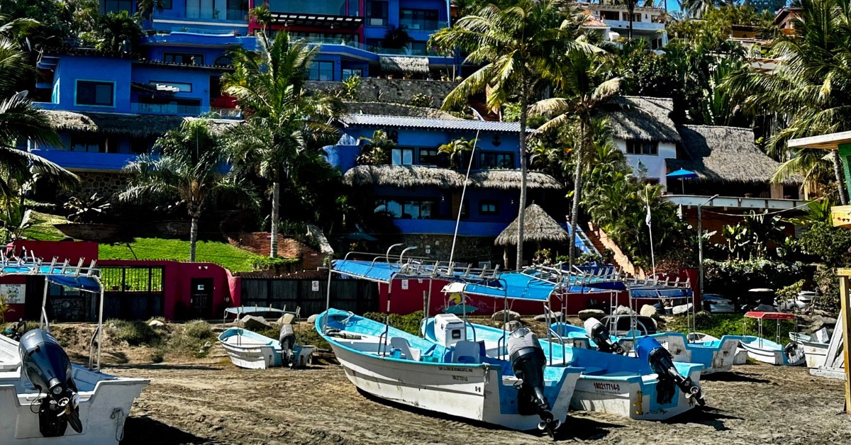 Boats on a beach in front of a hotel.