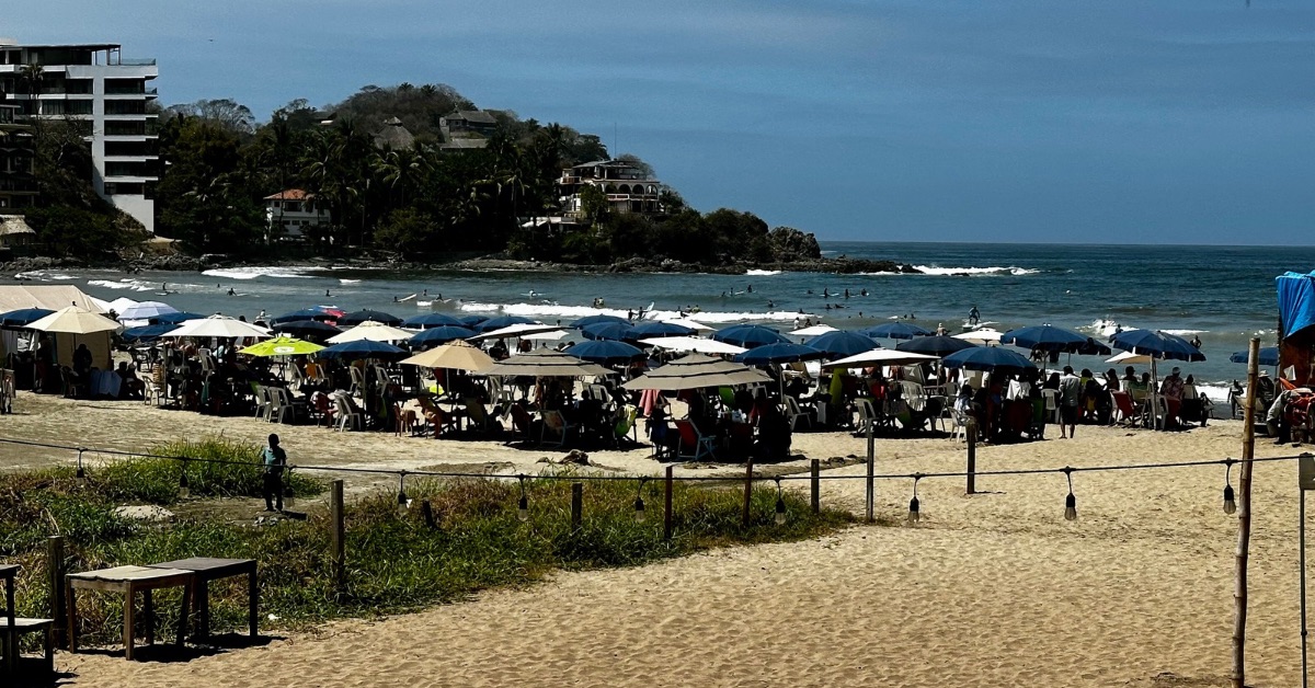 view of a beach full of sun loungers and people relaxing.