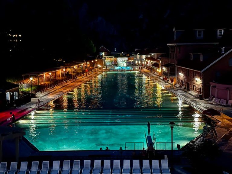 Unique Things To Do In Glenwood Springs at Night is to bathe in this massive hot springs mineral pool under starlight. The lights create yellow, orange and blue colors around the poolside.