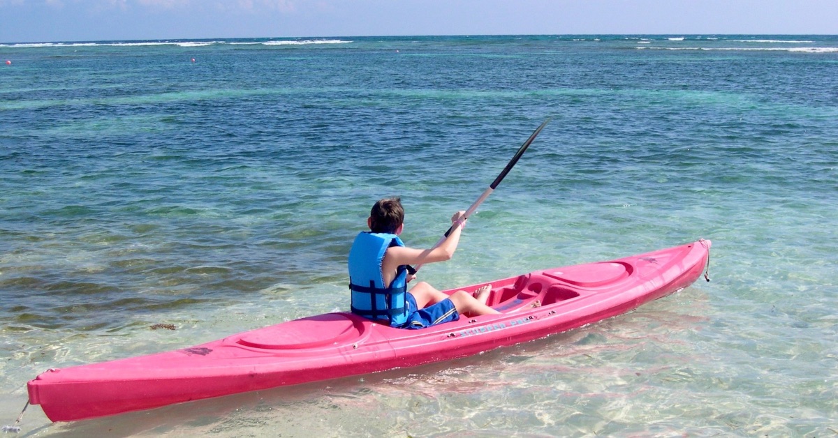 Child kayaking in shallow water.