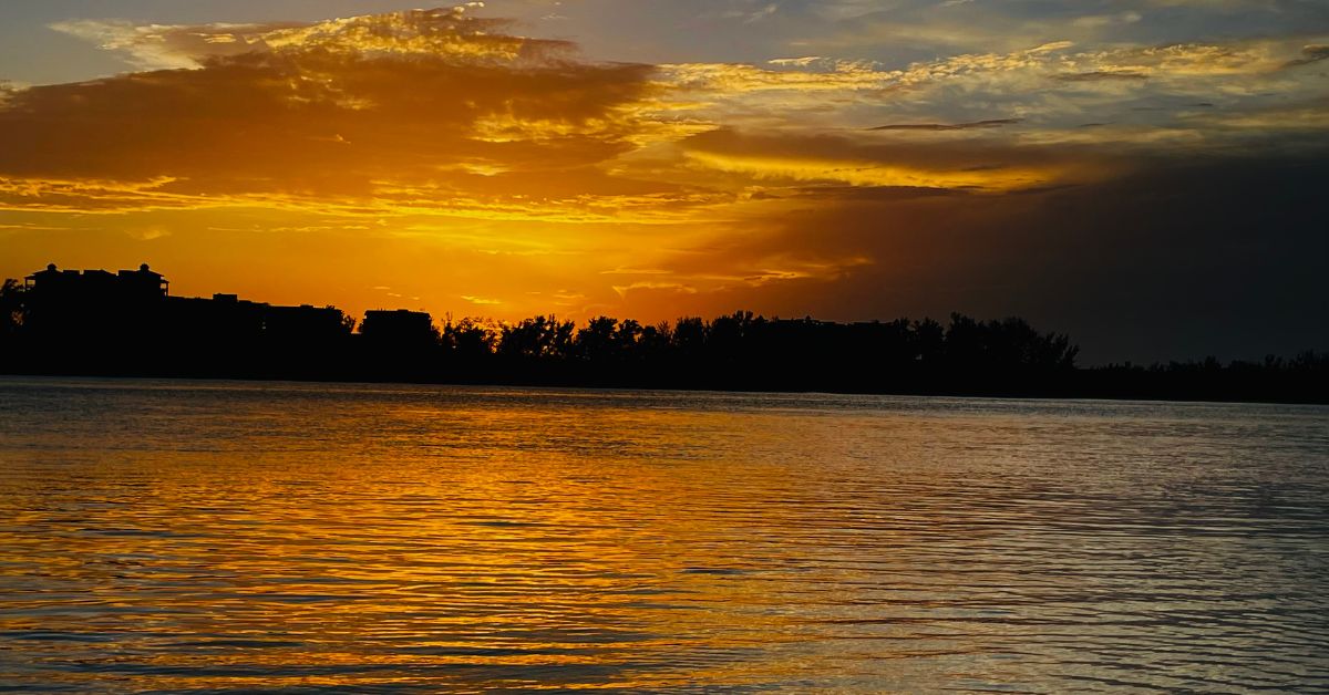 Sunset casting orange hue over the coastline and waters of Sarasota Bay.