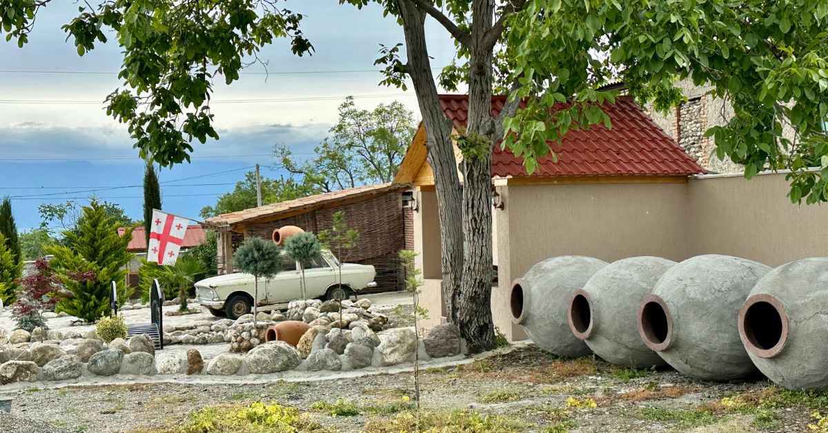 A countryside wine makers home with wine clay pots sitting next to the house.